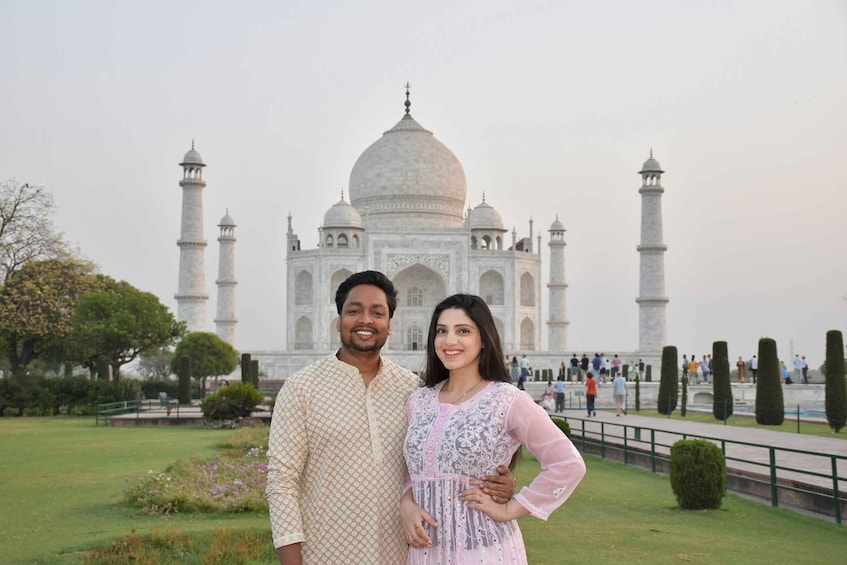 A couple standing in front of the Taj Mahal with the monument in the background. 1