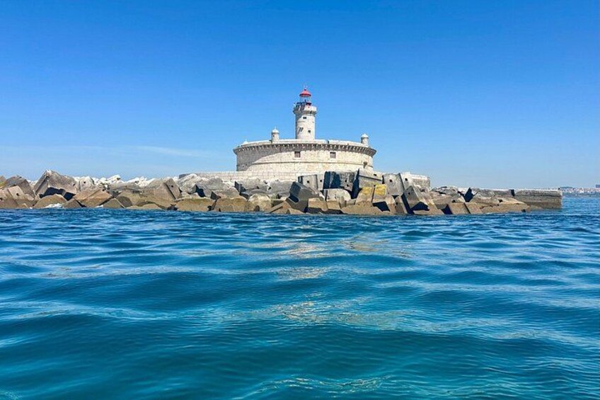A lighthouse on a rocky pier with clear blue water. 5