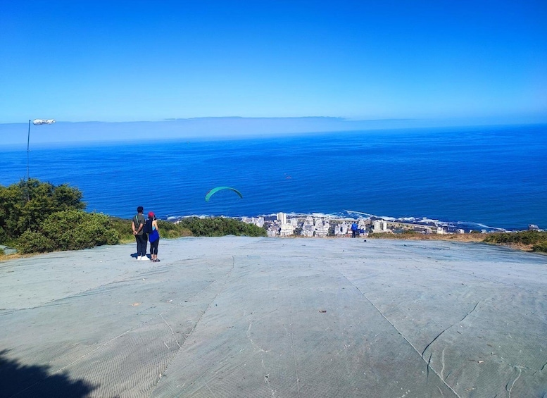 Paesaggio costiero con cielo azzurro limpido, una persona con una fotocamera e una città in lontananza. 2