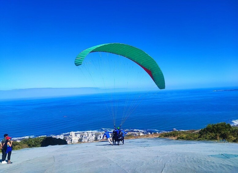 Un parapendio con vela verde che sorvola una città costiera. 4