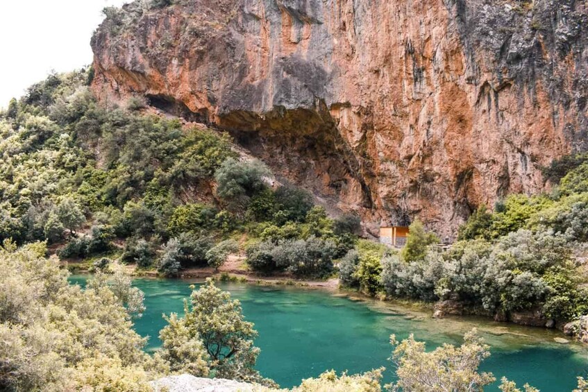 A river flowing through a mountainous area with dense vegetation and a rocky cliff. 4
