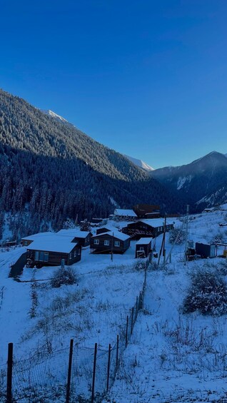 A snowy mountain village with wooden houses and a clear blue sky. 5