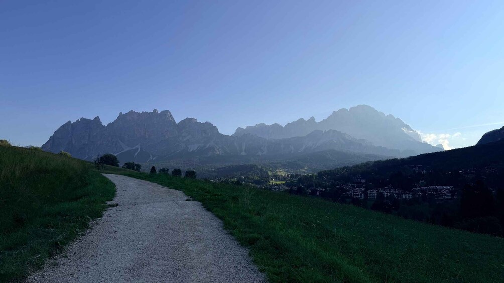 A gravel path winding through a mountainous landscape with a village in the valley below. 4