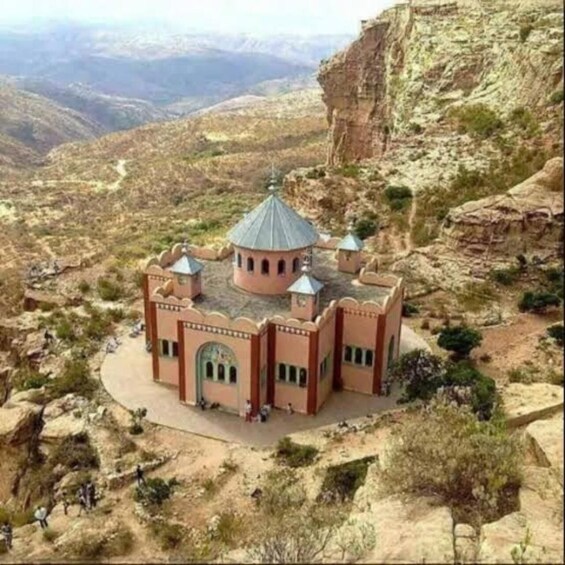 A small, isolated building with a dome and arched windows, surrounded by rocky terrain and sparse vegetation. 5