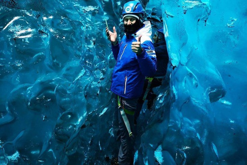 A person in a blue jacket and helmet, holding a stick, standing in a blue icy environment. 5