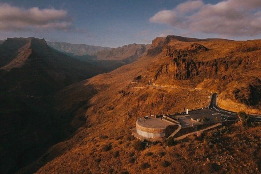 A mountainous landscape with a winding road and a circular building structure. 3