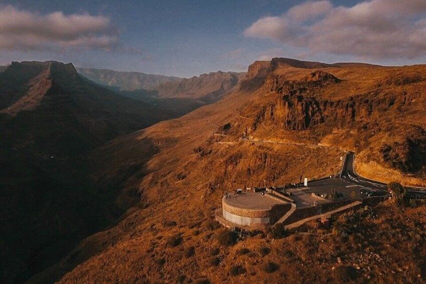 A mountainous landscape with a winding road and a circular building. 3