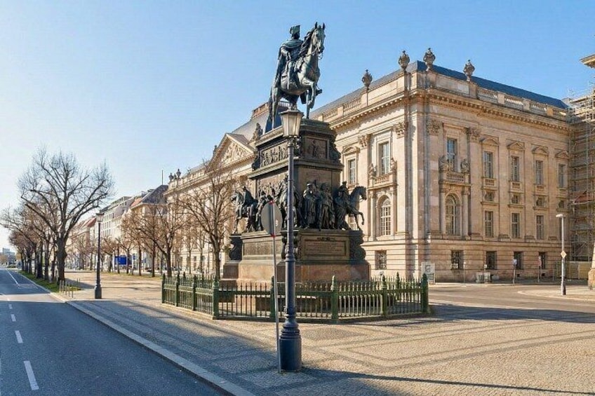 A statue on a pedestal, a large classical building, and a clear sky. 4