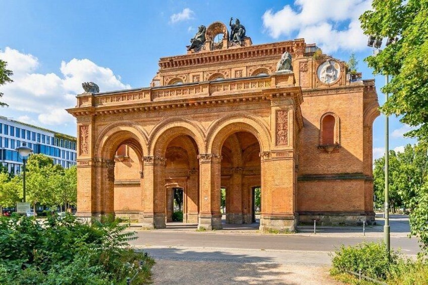 A historic brick building with arches and statues. 1