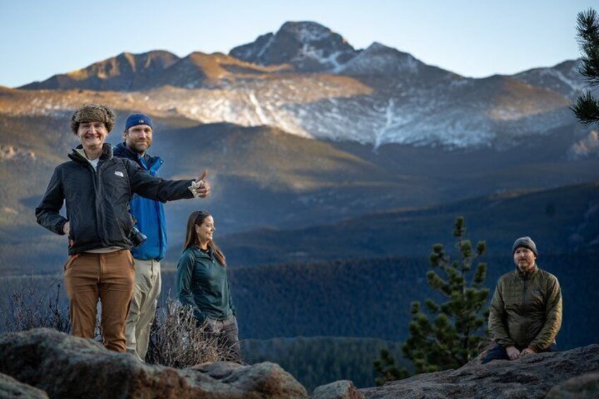 A group of people standing on a rocky outcrop with a mountainous landscape in the background. 3