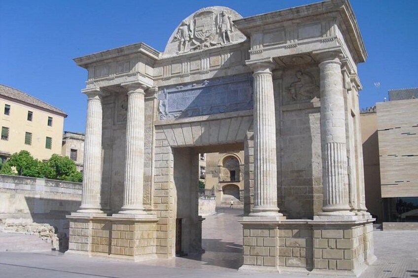 A classical stone archway with columns and relief sculptures, set in an urban environment. 3