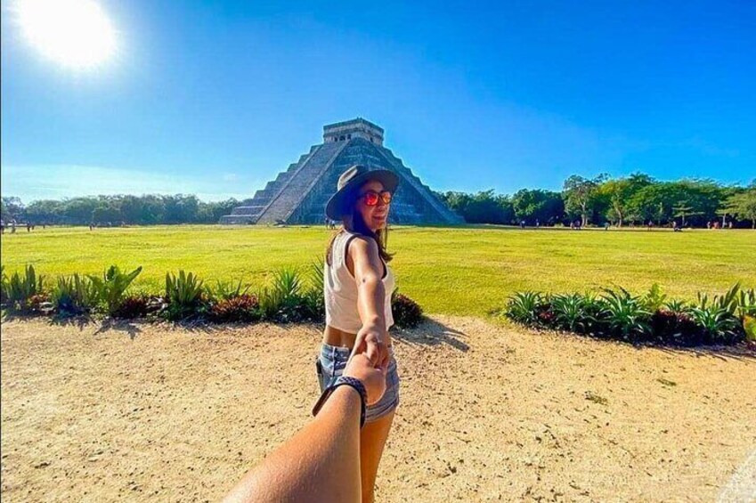 A person holding hands with another, standing in front of a large pyramid-like structure. 1