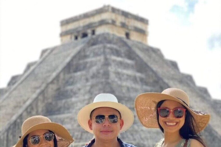 Three people in front of a large pyramid-like structure. 2
