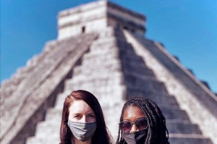 Two people standing in front of a large pyramid structure. 4