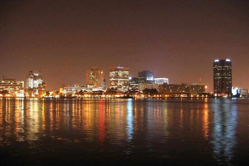 A city skyline at night with illuminated buildings reflecting on the water. 1