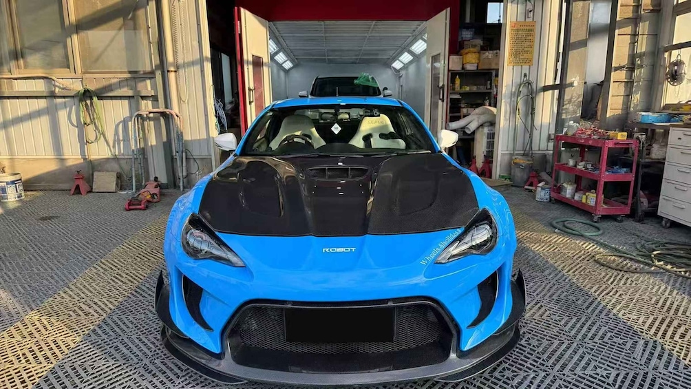 A blue sports car in a garage with tools and equipment around. 2