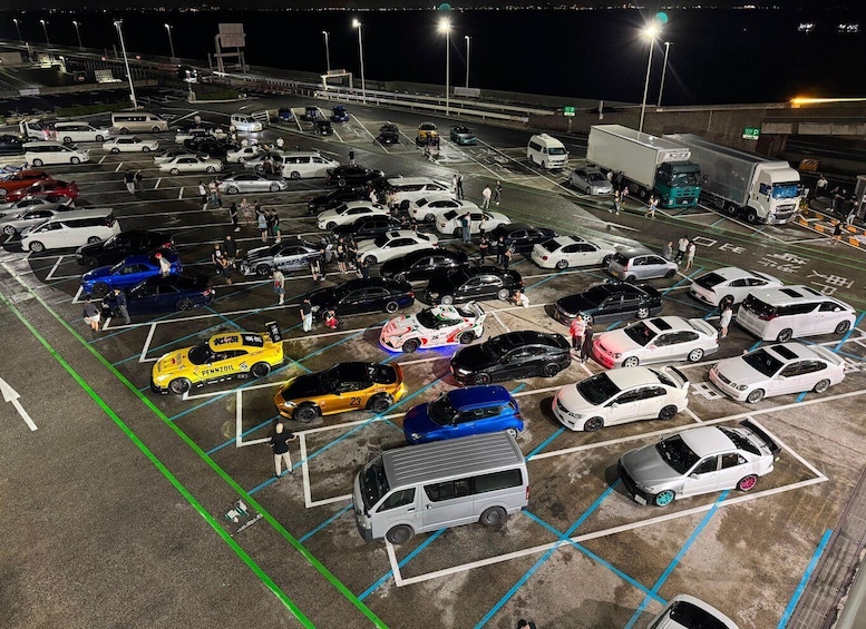 A parking lot at night with various cars and a few trucks. 3