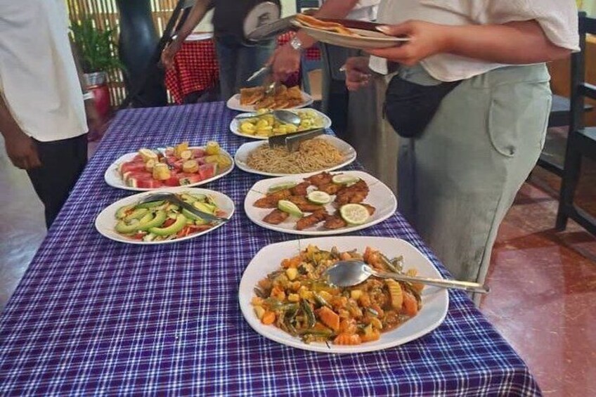 A table with various dishes, including salads, meats, and a large plate of mixed vegetables. 3