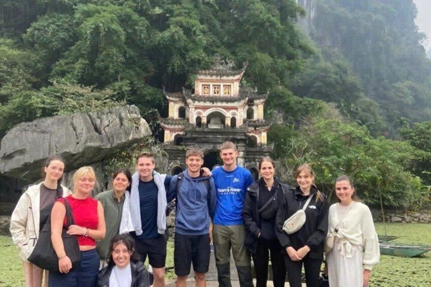 A group of people standing in front of a traditional Chinese temple with a rocky backdrop. 4