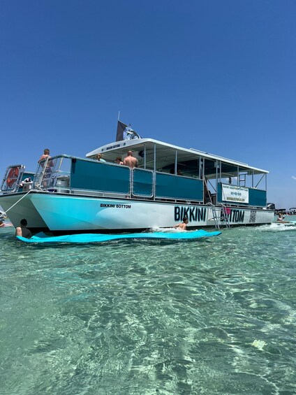 A boat named BIKKINI BOTTOM on clear blue water. 3