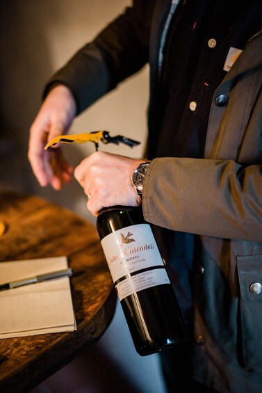 A person opening a bottle of wine with a corkscrew. 3