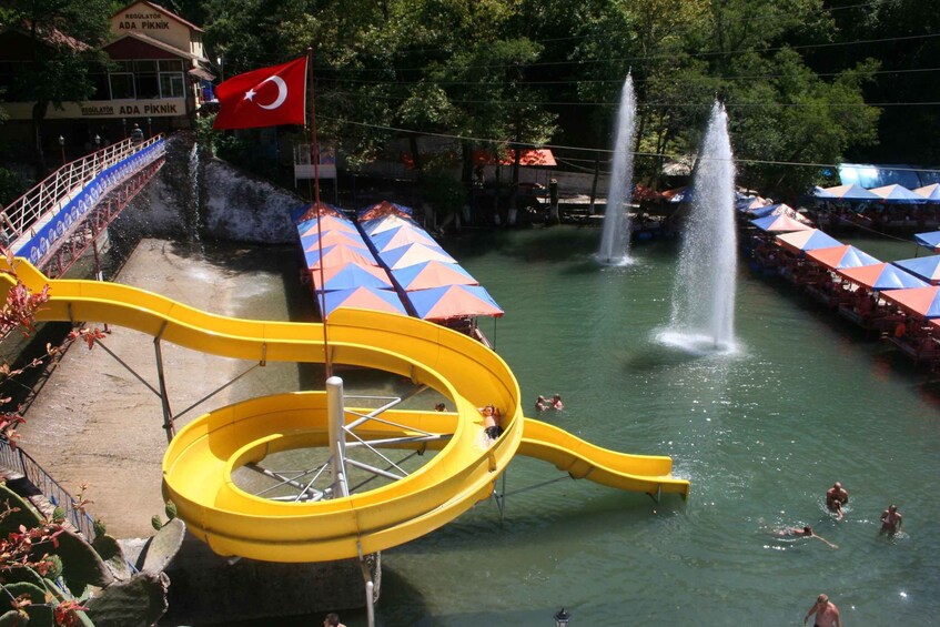 A water park with a yellow slide, multiple fountains, and a flag. 2