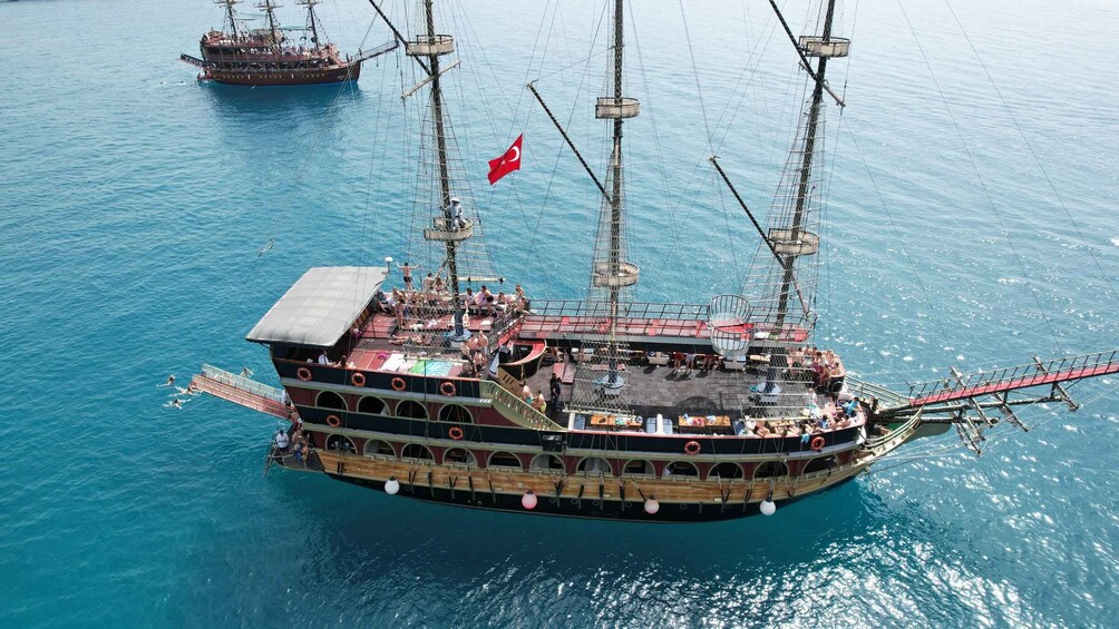 A large, multi-decked ship with a Turkish flag, anchored in calm blue waters. 1