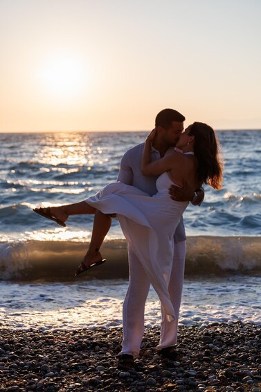 A couple embracing on a pebbled beach at sunset. 5