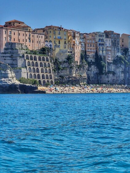 A coastal town with buildings on a cliff, a beach, and the sea. 5