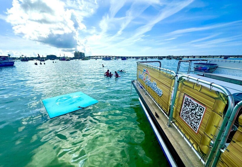 A boat with a QR code, a blue mat, and people swimming in the water. 1