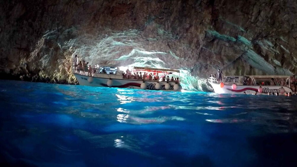 A boat tour in a cave with clear blue water and rocky walls. 1