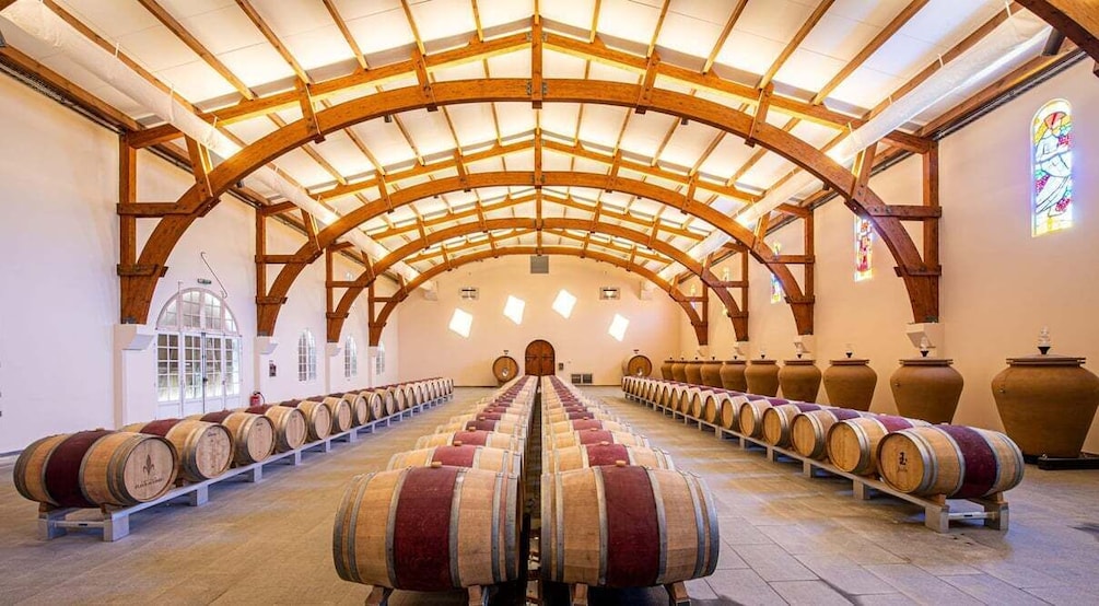 A wine cellar with wooden barrels and a vaulted ceiling. 1