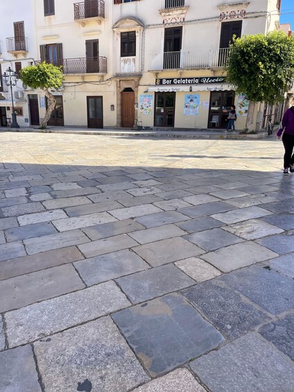 A paved square with stone tiles, a bar gelateria, and a building with balconies. 3