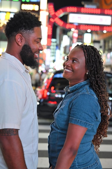 A couple standing in a busy urban street with bright lights and vehicles in the background. 5