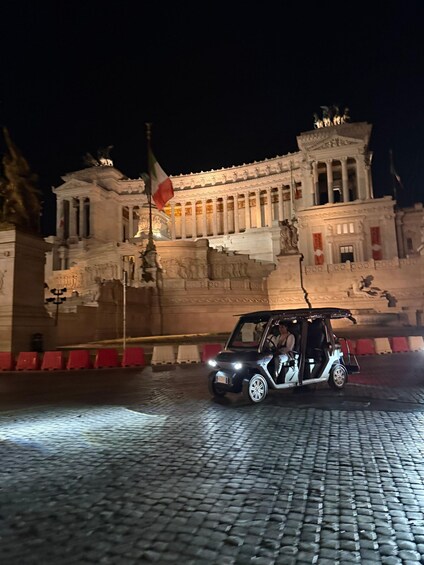A historic building with classical architecture, a flag, and a vehicle on a cobblestone street. 4