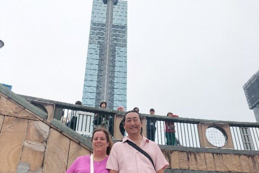 A tall glass skyscraper, a stone wall, and a metal railing. 4