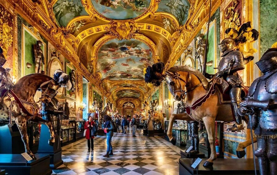 A grand hall with ornate golden ceilings, large horse statues, and classical paintings. 2