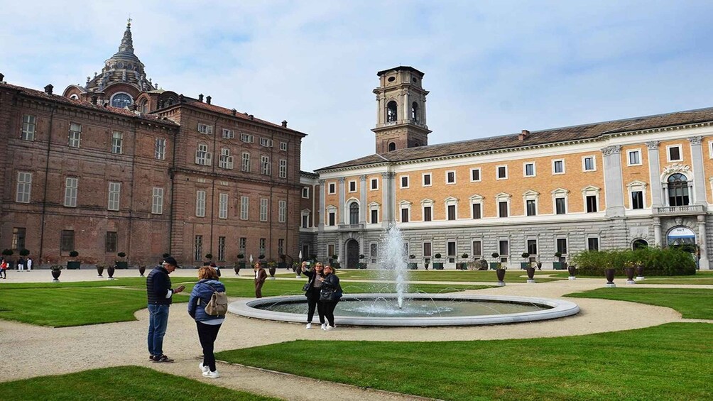 A courtyard with a fountain, historic buildings, and a clock tower. 5