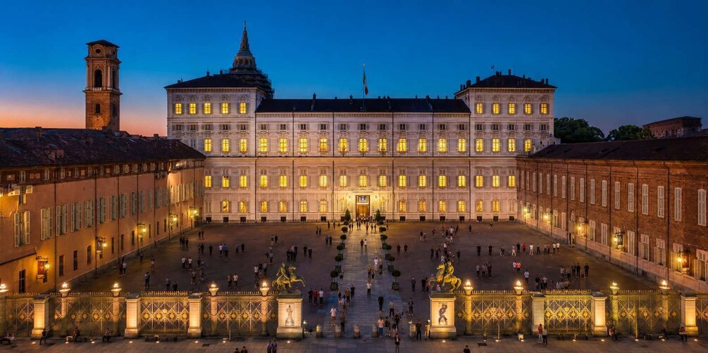 A grand historic building with a central courtyard, ornate gates, and a statue. 1