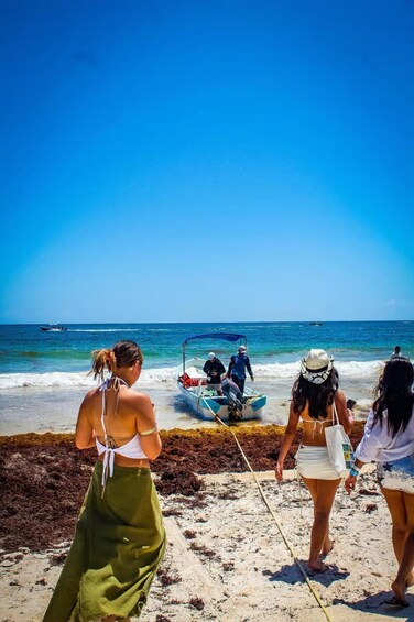 A beach with people walking towards a boat on the shore. 5