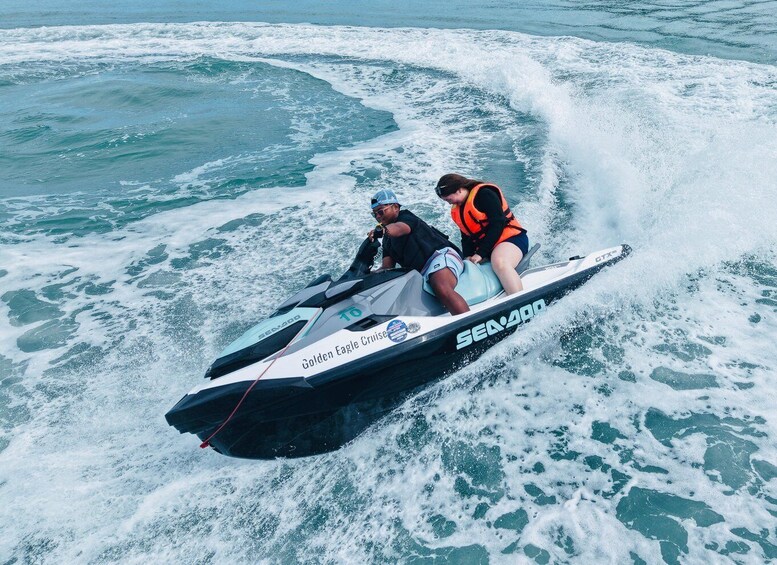 Two people on a Sea-Doo jet ski, riding through ocean waves. 5