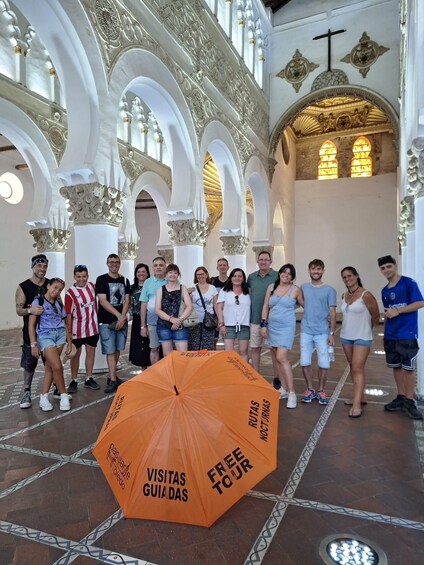 A group of people standing in a historic building with ornate arches and columns. 2