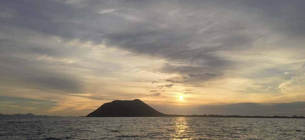 A sunset over a body of water with a mountain silhouette. 5