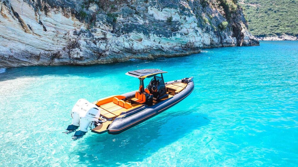 A motorboat on clear turquoise water with a rocky cliff in the background. 1