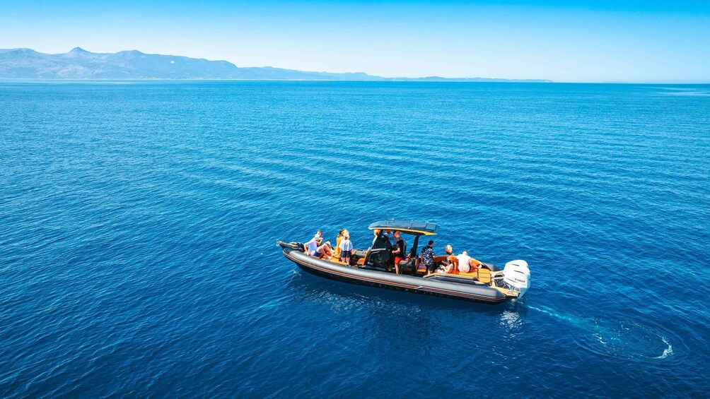 A boat with passengers on a calm sea with distant mountains. 2
