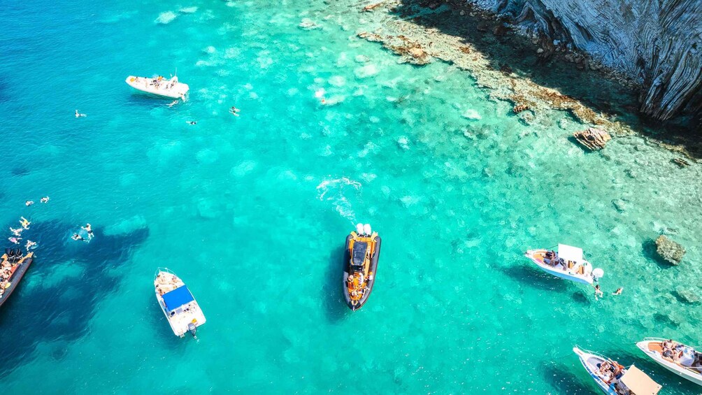A turquoise sea with boats and swimmers. 4