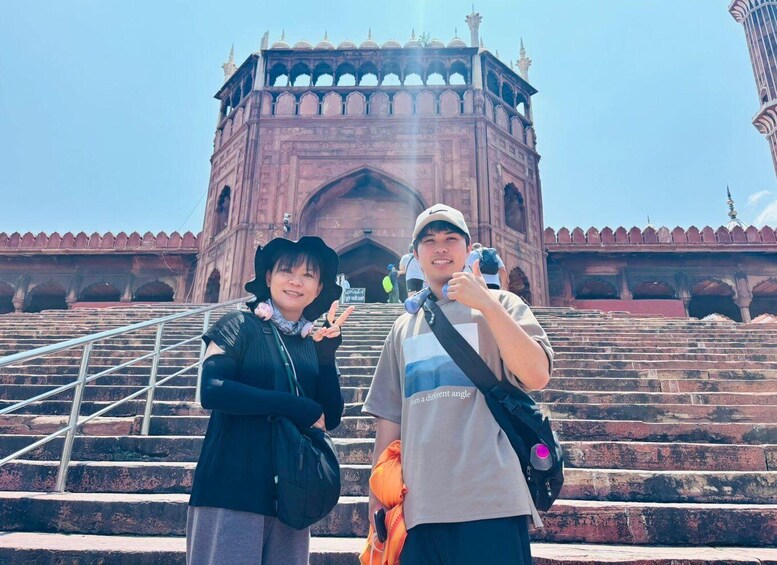 Two people standing in front of a large, ornate building with multiple arches and steps leading up to it. 4