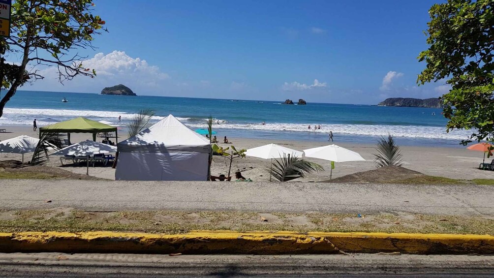 A beach with umbrellas, a tent, and a clear view of the ocean. 3