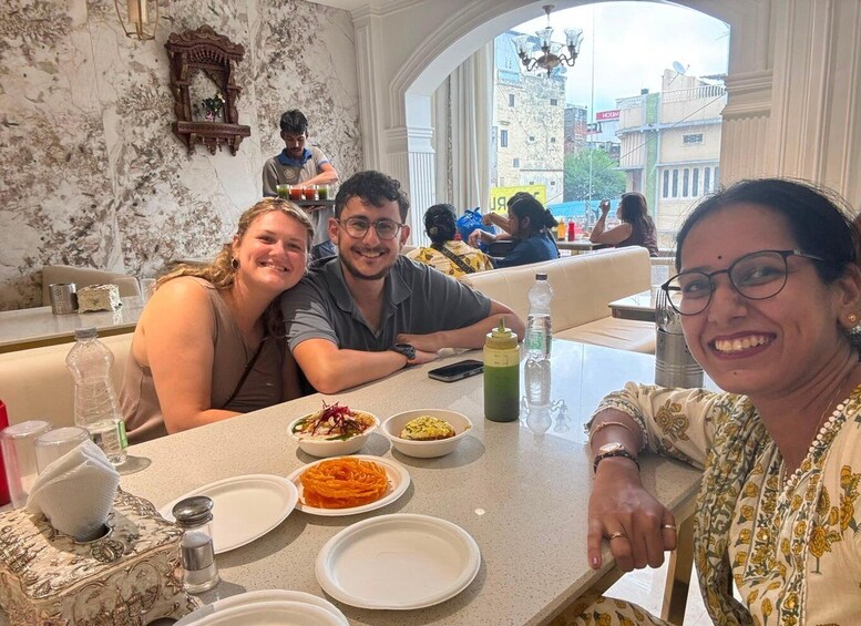 A group of people dining at a restaurant with a marble wall and a view of buildings outside. 2