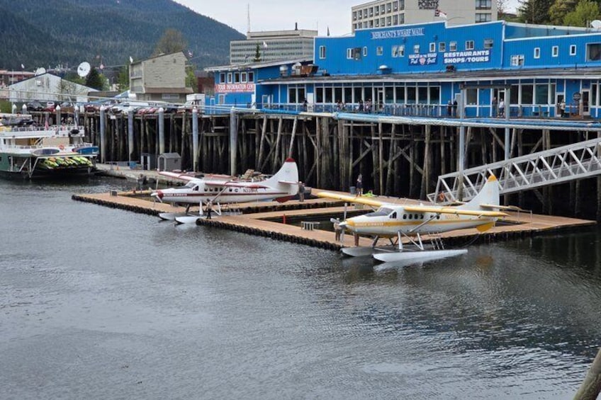 A waterfront with a dock, a blue building with signage, and a small white boat. 2
